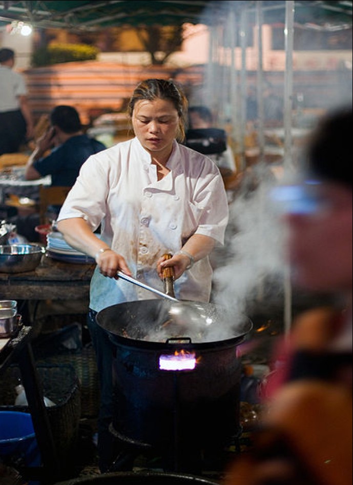 Hawker chef cooking in a wok over flame