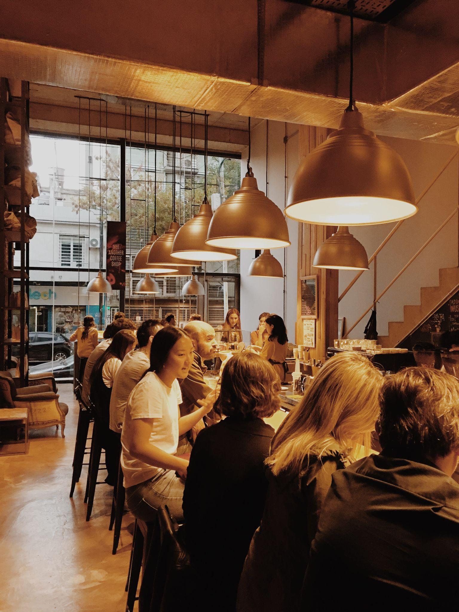 Diners under copper pendant lights in a busy restaurant