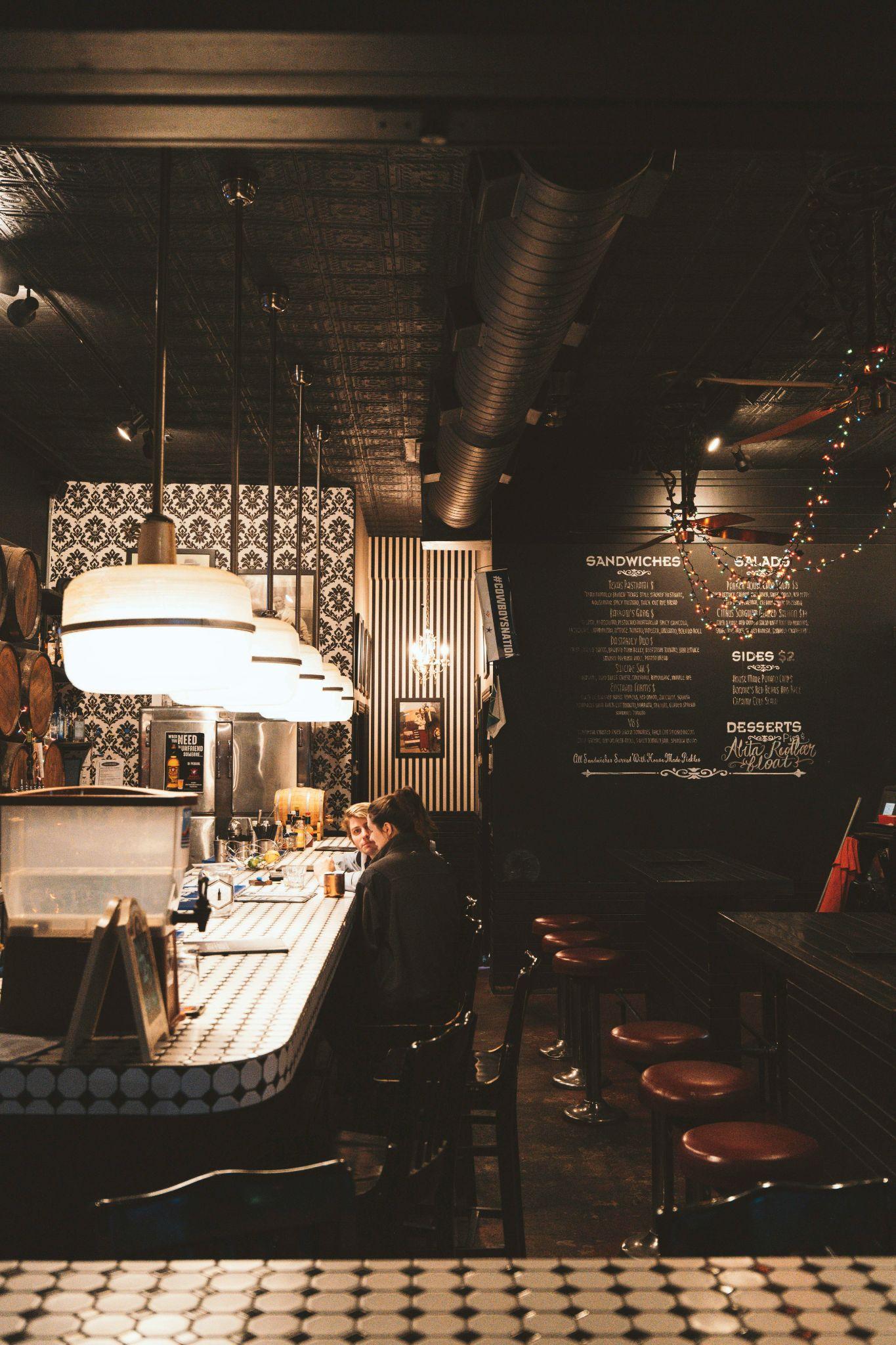 Patterned-wall bistro interior with chandelier and guests at the bar