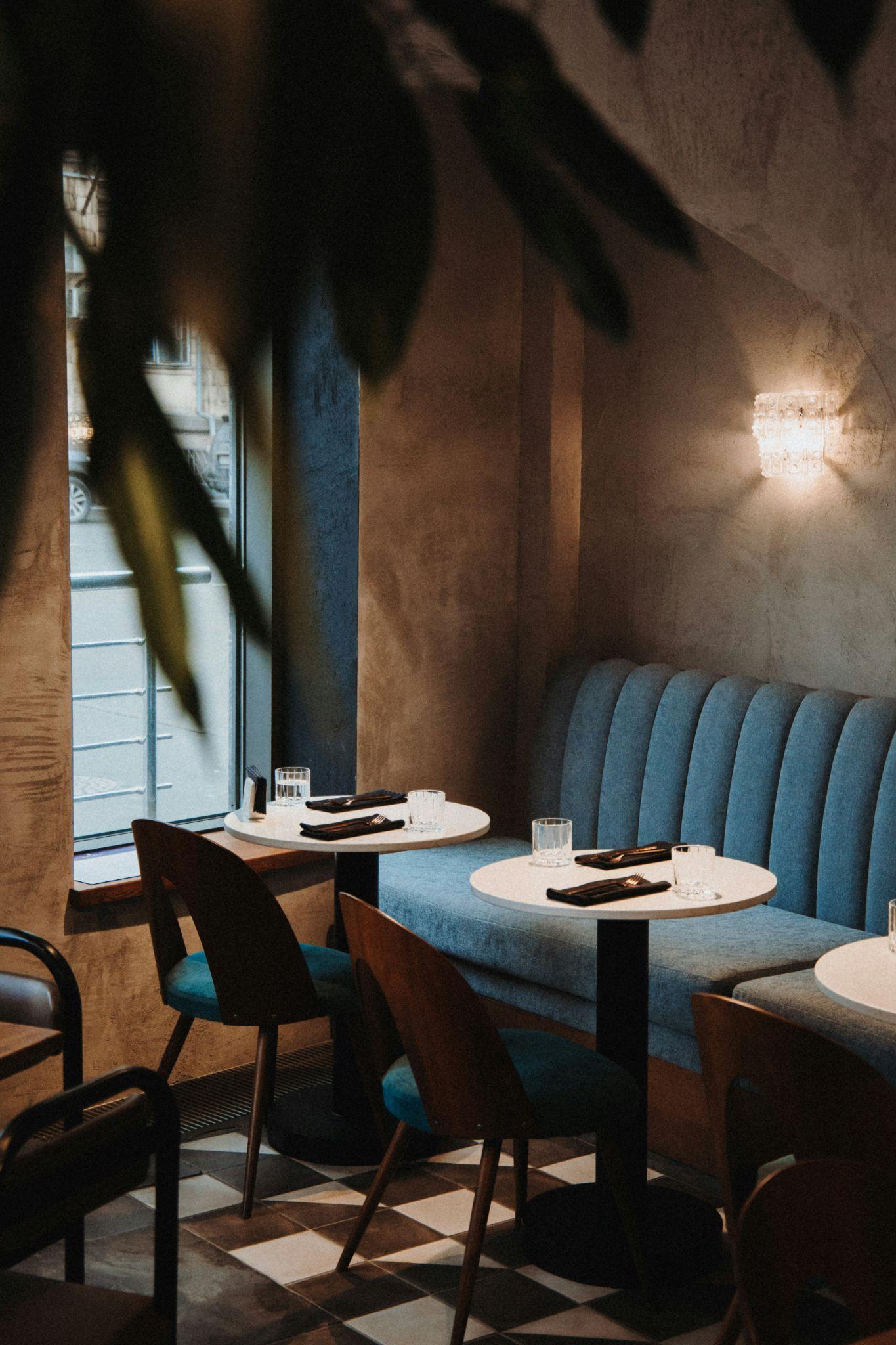 Intimate dining nook with arched blue banquette and tonal walls